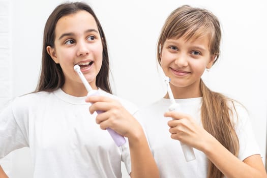 Portrait of two beautiful girls kids with perfect smile holding toothbrushes. Child dental care, oral hygiene concept. High quality photo