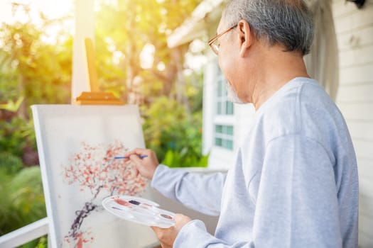 Lifestyle elderly people smile paint at his easel outside home, Asian senior old man painting picture using brush and oil color on canvas, Happy retirement artist and activity concept