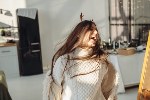 Surrounded by sunlight, a bright young lady dons a Christmas reindeer mask. High quality photo