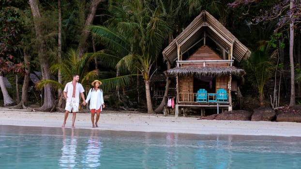 Koh Wai Island Trat Thailand near Koh Chang. couple walking in front of a wooden bamboo hut bungalow on the beach. a young couple of men and woman on a tropical Island in Thailand