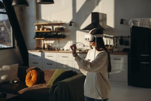 Playing an online game, a lovely young lady enjoys her VR headset in the apartment. High quality photo