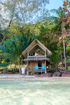 Koh Wai Island Trat Thailand is a tinny tropical Island near Koh Chang. wooden bamboo hut bungalow on the beach. a young couple of men and woman at a bamboo hut on a tropical Island in Thailand