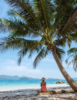 Koh Wai Island Trat Thailand is a tinny tropical Island near Koh Chang. a young woman on a tropical beach during a luxury vacation in Thailand. woman sitting under a palm tree