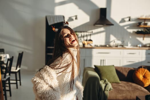 Engaged in sunlight, a bright young woman embraces a Christmas reindeer mask. High quality photo