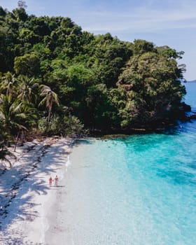 Drone aerial view at Koh Wai Island Trat Thailand near Koh Chang. a young couple of men and women on a tropical beach during a luxury vacation in Thailand walking at the beach