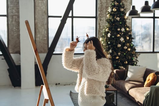 A joyful expression graces the face of a lively young woman in a Christmas reindeer mask at home. High quality photo