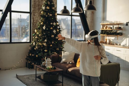 Engrossed in an online game, a lovely young lady wears a virtual reality headset in her apartment. High quality photo