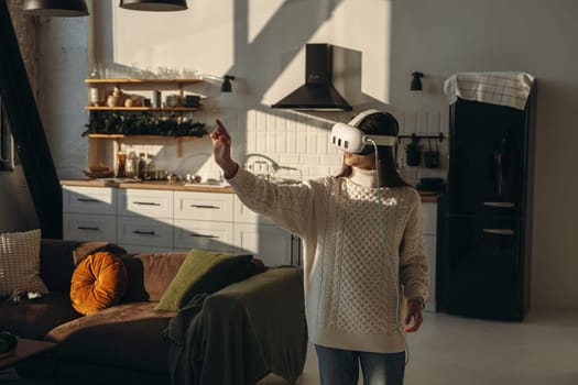 A young lady, absorbed in an online game, wears a virtual reality headset in her apartment. High quality photo