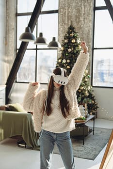 Embracing the festive spirit, a beautiful young lady uses a VR headset near a Christmas tree. High quality photo