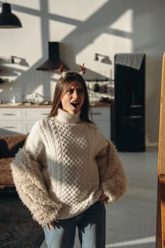 Amidst sunlight, a lively young woman wears a Christmas reindeer mask at home. High quality photo