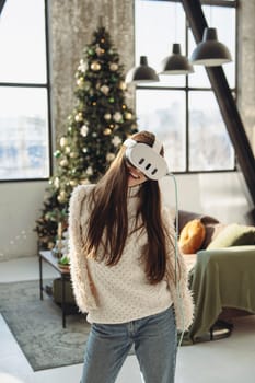 A beautiful young woman in a virtual reality headset against the backdrop of a Christmas tree. High quality photo