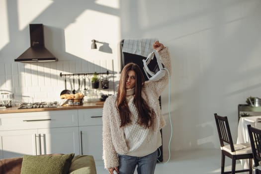 With grace, a beautiful young lady holds a virtual reality headset. High quality photo