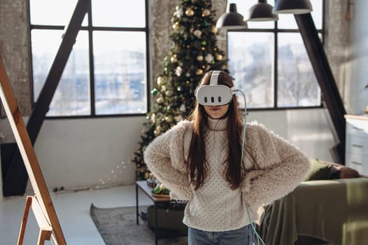 A bright young woman in a virtual reality headset in front of the mirror on a sunny day. High quality photo