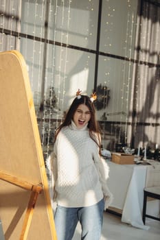 Radiating cheer, a lively young woman dons a Christmas reindeer mask and smiles in the apartment. High quality photo