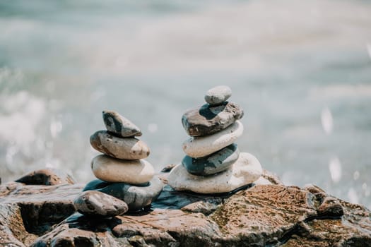 Pyramid stones on the seashore with warm sunset on the sea background. Happy holidays. Pebble beach, calm sea, travel destination. Concept of happy vacation on the sea, meditation, spa, calmness.