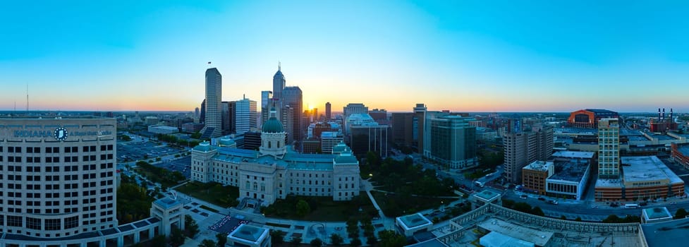 Sunrise over Indianapolis skyline, showcasing a blend of modern and historical architecture from an aerial perspective, captured by drone in 2023