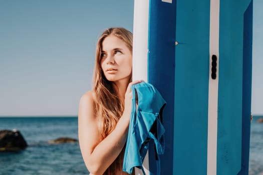 Close up shot of beautiful young caucasian woman with black hair and freckles looking at camera and smiling. Cute woman portrait in a pink bikini posing on a volcanic rock high above the sea