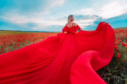 Woman poppy field red dress. Happy woman in a long red dress in a beautiful large poppy field. Blond stands with her back posing on a large field of red poppie