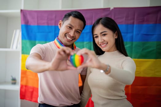 Young gay male and girl friend hands holding rainbow heart with smile face. LGBT, human rights and equality social.