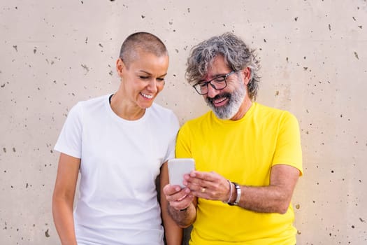 senior man and young woman smiling happy using a mobile phone, concept of technology of communication