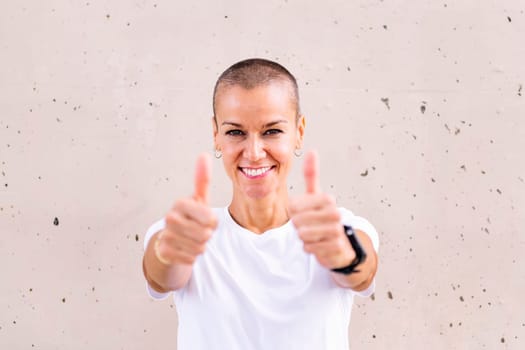 young woman with short hair smiling happy with with thumbs up looking at camera, copy space for text
