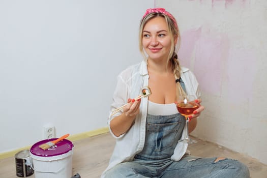 Sexy girl designer eats sushi on the construction site. painter has lunch after work. Concept interior design and room repair.