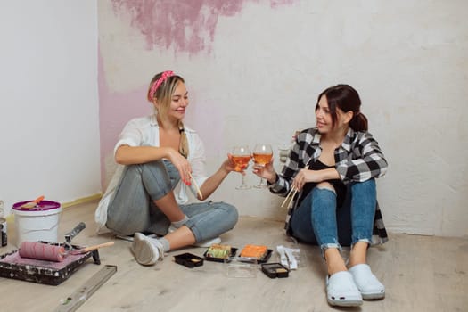 Two girlfriends cute girls eat sushi after working with the repair of the room. The LGBT family is renovating the room. Painters' lunch.