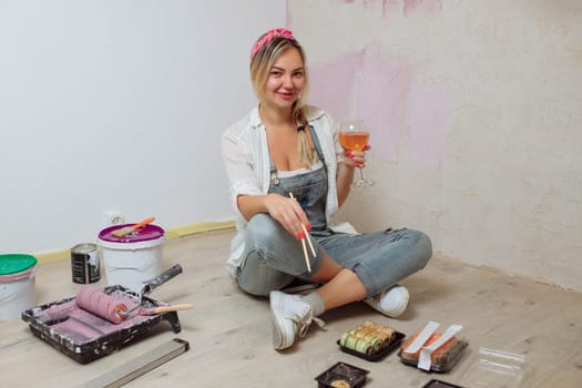 Sexy girl designer eats sushi on the construction site. painter has lunch after work. Concept interior design and room repair.