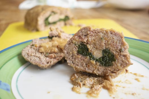 spinach meatloaf cut in half placed on a yellow cutting board