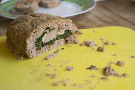 spinach meatloaf cut in half placed on a yellow cutting board