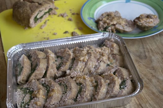 slices of spinach-filled meatloaf lined up in an aluminum container