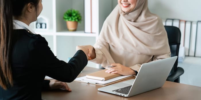 Real estate broker agent manager shaking hands with a client after successful agreement in the office.