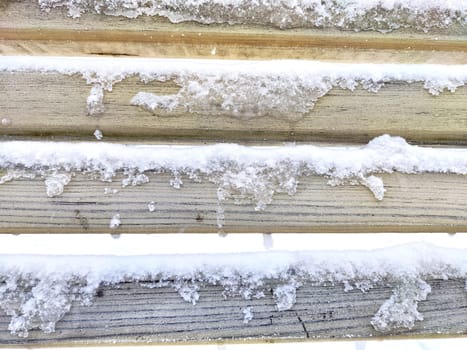 Snow on the crossbars of wooden bench. Abstract background, texture, pattern, frame, place for text, copy space