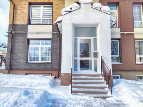 Stairs with steps and railings to the entrance to house in winter and snow in winter. Beautiful entrance, background, location