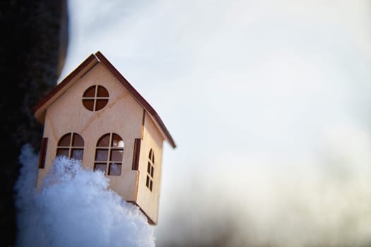 Wooden toy house on snow, natural abstract background. winter season concept. symbol of cozy, loving family home. construction, sales, rental concept. Christmas and new year holidays. copy space