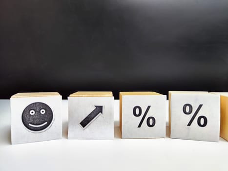 Wooden cubes in a column and row with white signs with a smiley sign, an arrow, a percentage. The concept of positivism. Positive thinking leads to the achievement of results and profits