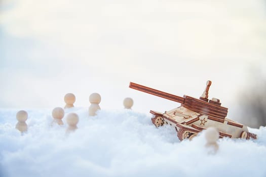 Wooden toy Russian tank T-34 and little men in the snow. Russia and Ukraine are at war in winter. Encirclement, retreat, attack, victory