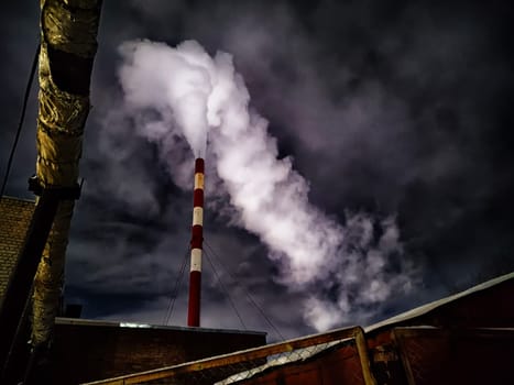 Winter night industrial landscape. Coal-fired power station with smoking chimneys against dramatic dark sky. Carbon dioxide CO2 emissions as primary driver of global climate change. Air pollution