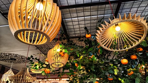 Yellow wicker chandeliers on the ceiling and an orange tree with tangerines. Interior, room design, cute, warm background