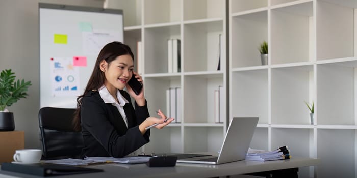 Happy confident businesswoman talking on the phone. Smiling female business person talking work using talking on the phone at office sitting at desk.