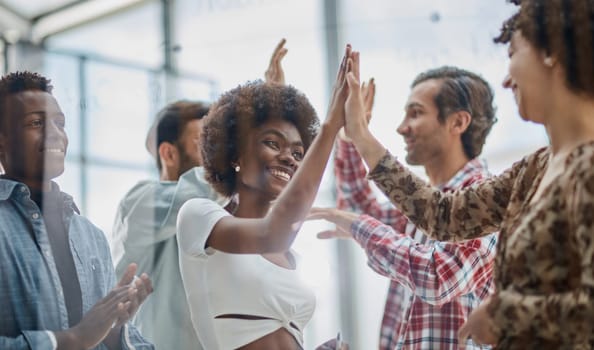 Excited multiracial employees give high five engaged in teambuilding activity in office together