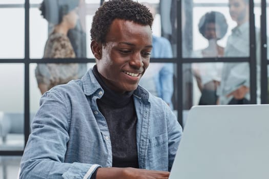 smiling leader business man with executives working on laptop in background.