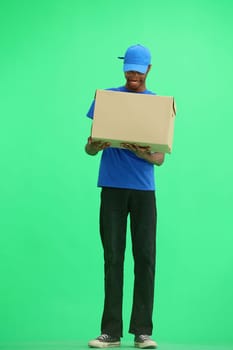 A male deliveryman, on a green background, full-length, with a box.