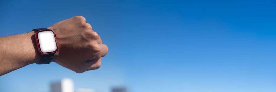 Male hand wearing and showing smartwatch mockup on sky buildings minimal background. High quality photo