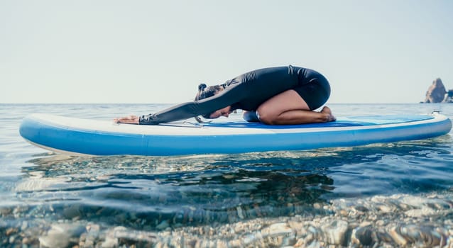 Woman sup yoga. Middle age sporty woman practising yoga pilates on paddle sup surfboard. Female stretching doing workout on sea water. Modern individual hipster outdoor summer sport activity