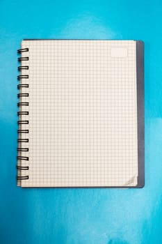Blank sheet of notebook on a blue background, copy space