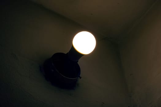 Light of an old light bulb on a wall in the dark close up