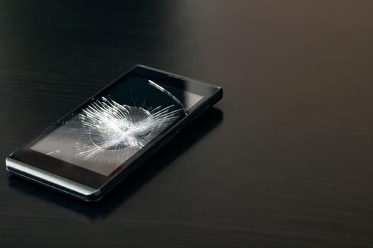 Broken display phone on a black wooden table