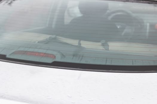 Hood of a white car with raindrops close up