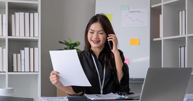 Cheerful Asian businesswoman talking on the phone working in modern office Happy Asian businesswoman company manager wearing a suit is talking on the phone